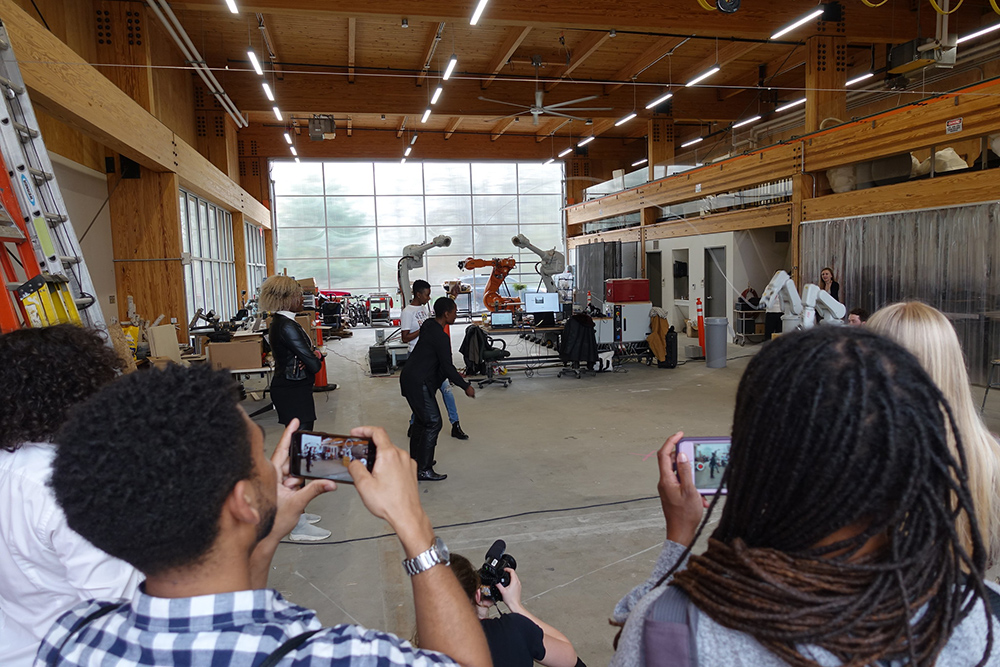 一张人们用手机拍摄的照片，有人用机器人手臂操纵跳绳。