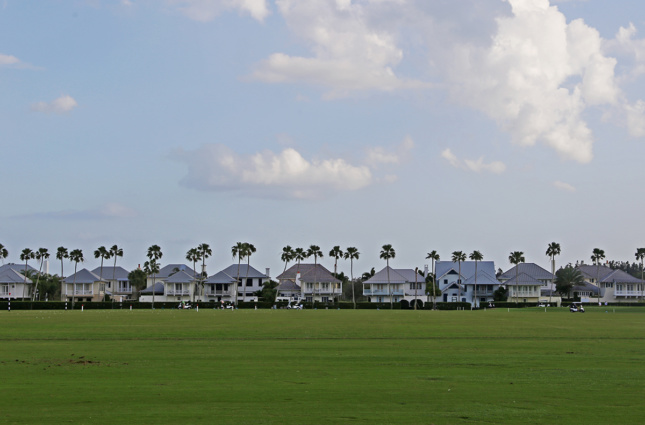 一排前面有高尔夫球场的大房子的照片