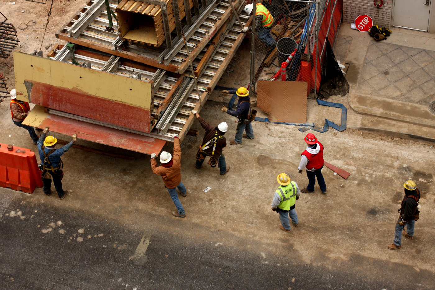 工人戴着安全帽和背心从卡车后面卸下建筑材料