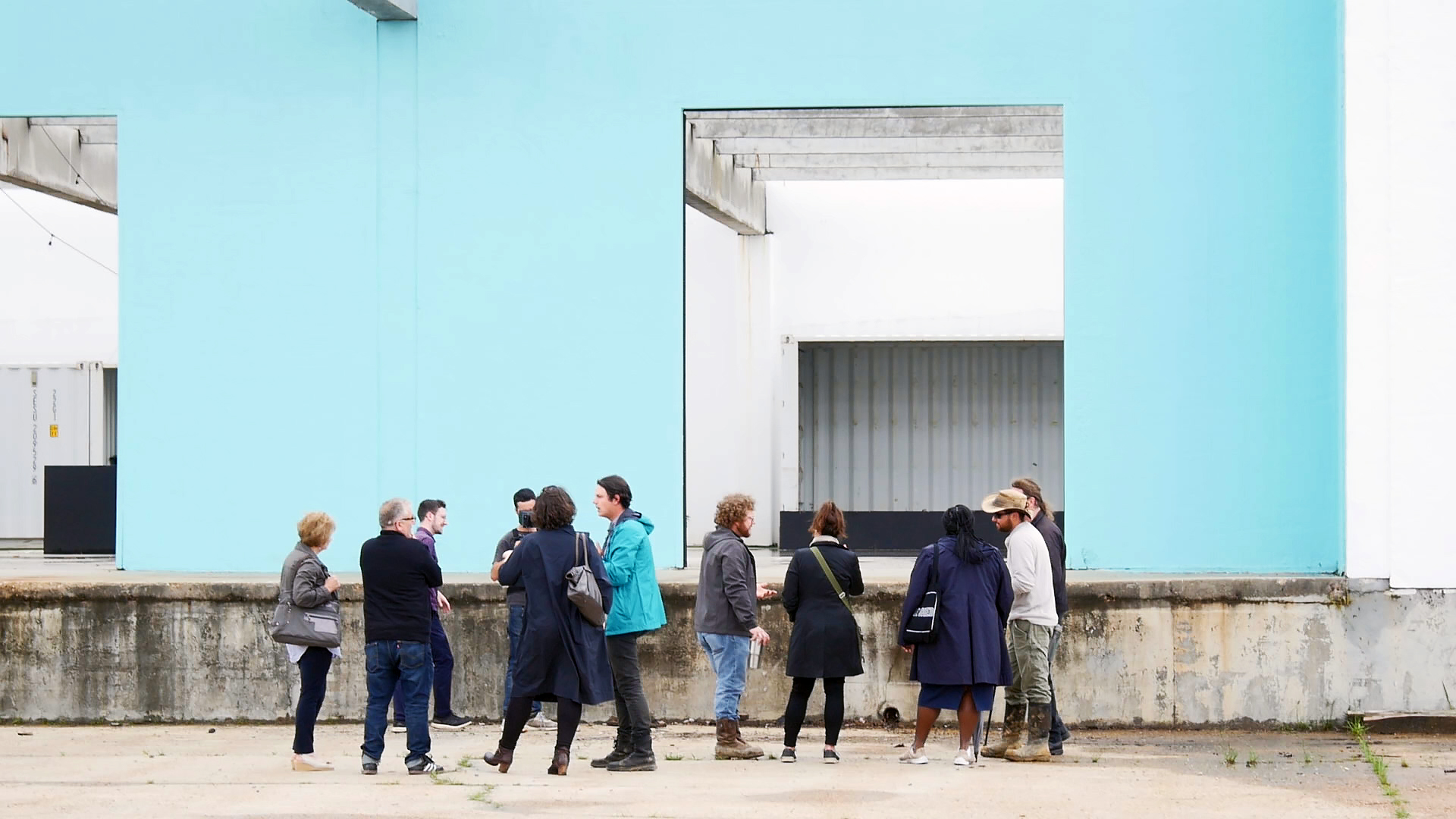 一张人们站在浅蓝色建筑墙前的照片