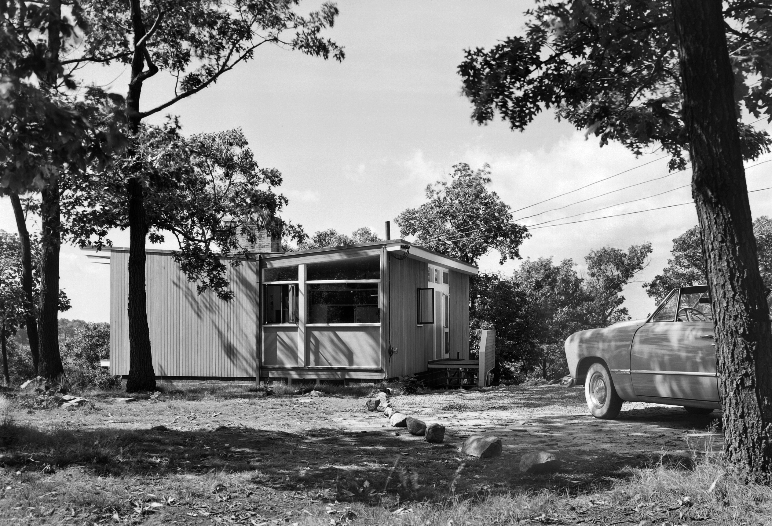 一个小屋的黑白照片有一辆汽车的在前面