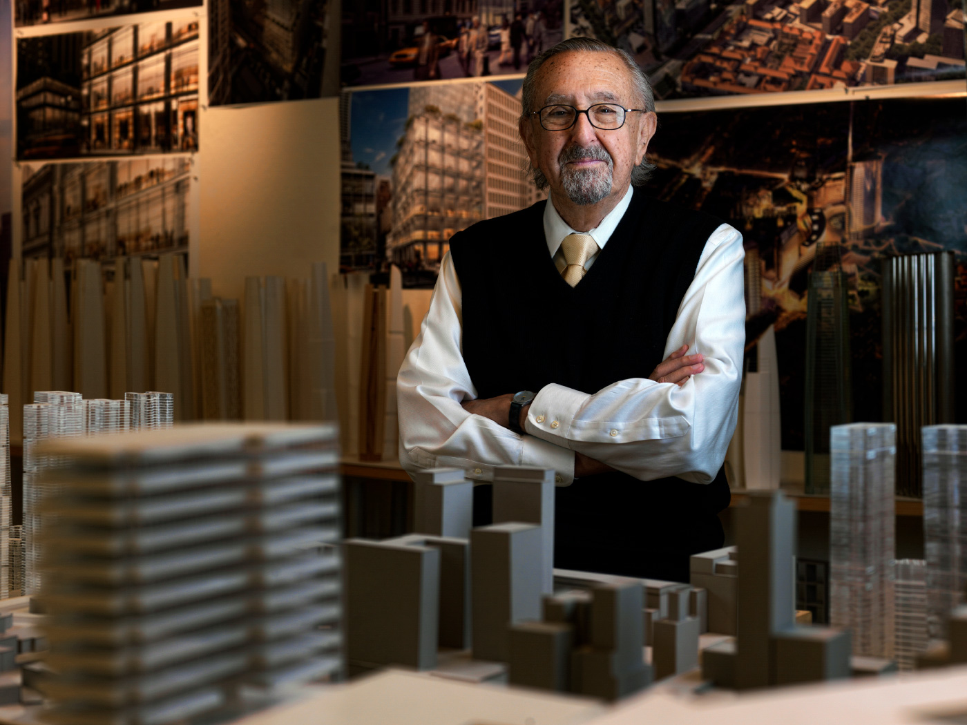一位年长的男子César Pelli站在建筑模型中间