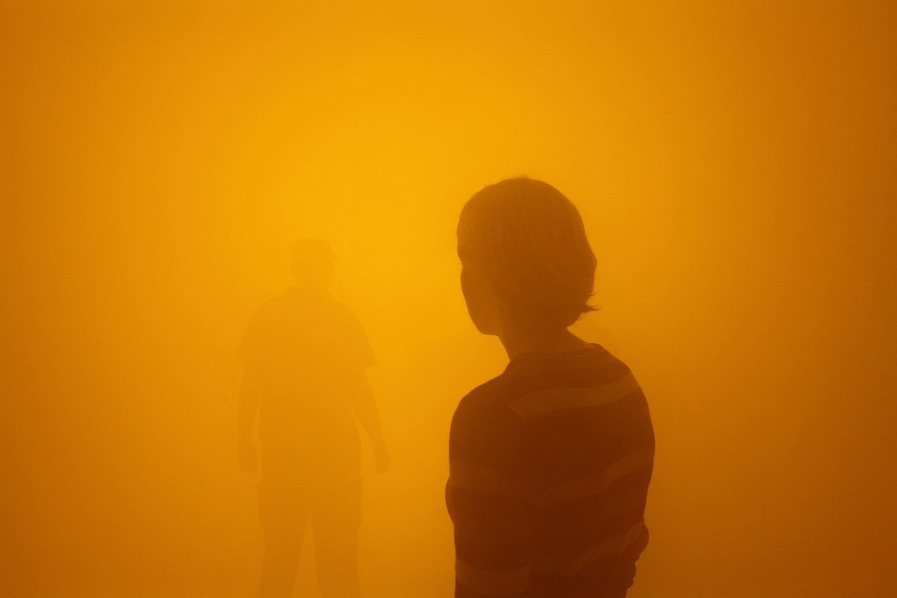 两个人在Olafur Eliasson Tate展示中徘徊在橙色雾中
