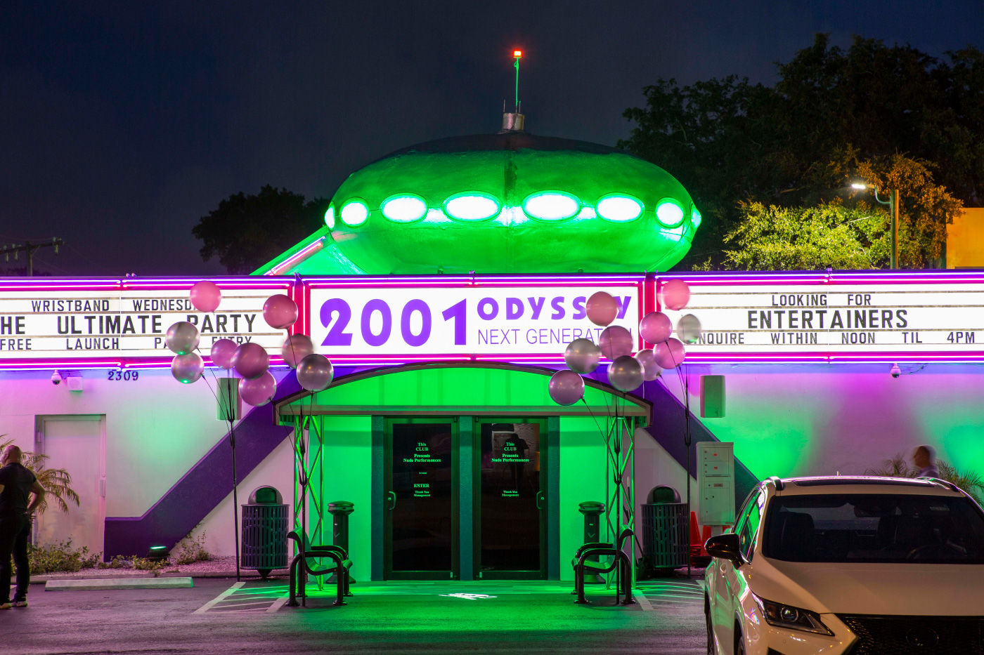 由绿色霓虹灯照亮的脱衣舞俱乐部与顶级的不明飞行物的未来房子