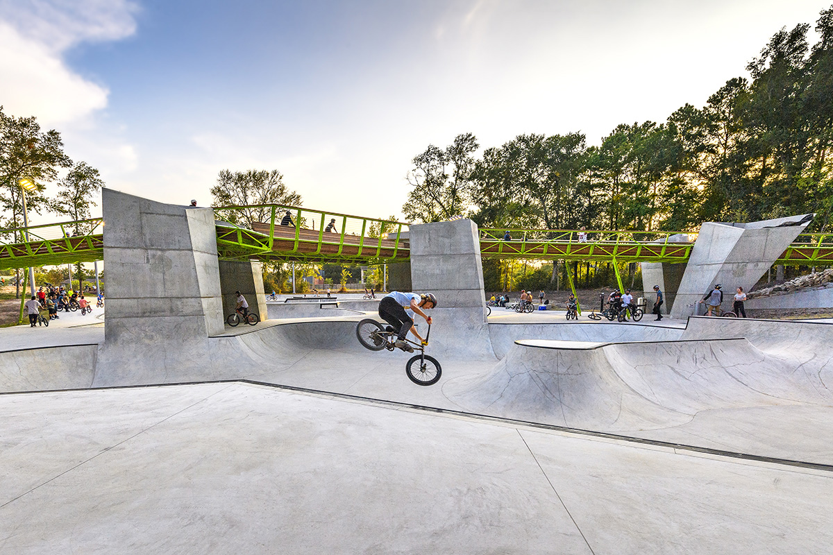 照片中是混凝土自行车碗，扭曲的绿钢桥穿过摇滚之星能源自行车公园