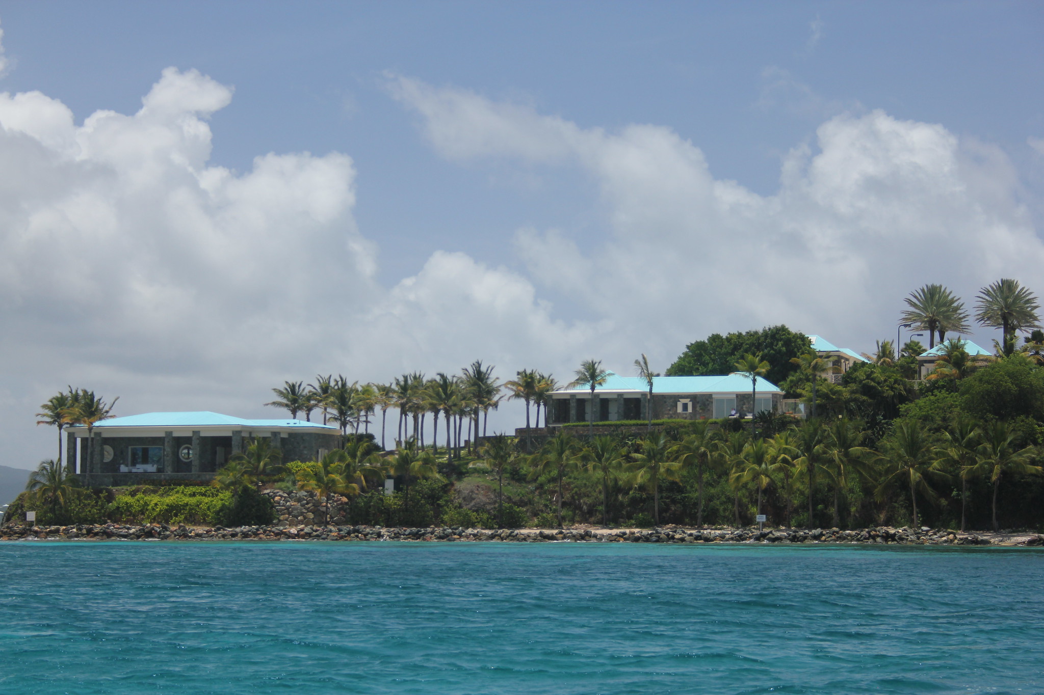 两座低矮的建筑坐落在一个棕榈树岛上，俯瞰着蓝色的海水，这是杰弗瑞·爱泼斯坦度假的地方