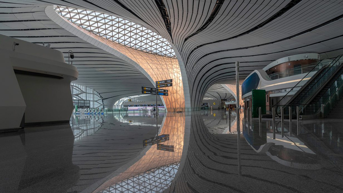 北京大兴国际机场的内部照片，光滑的白色地板和巨大的天窗位于登机口旁边的弧形墙上