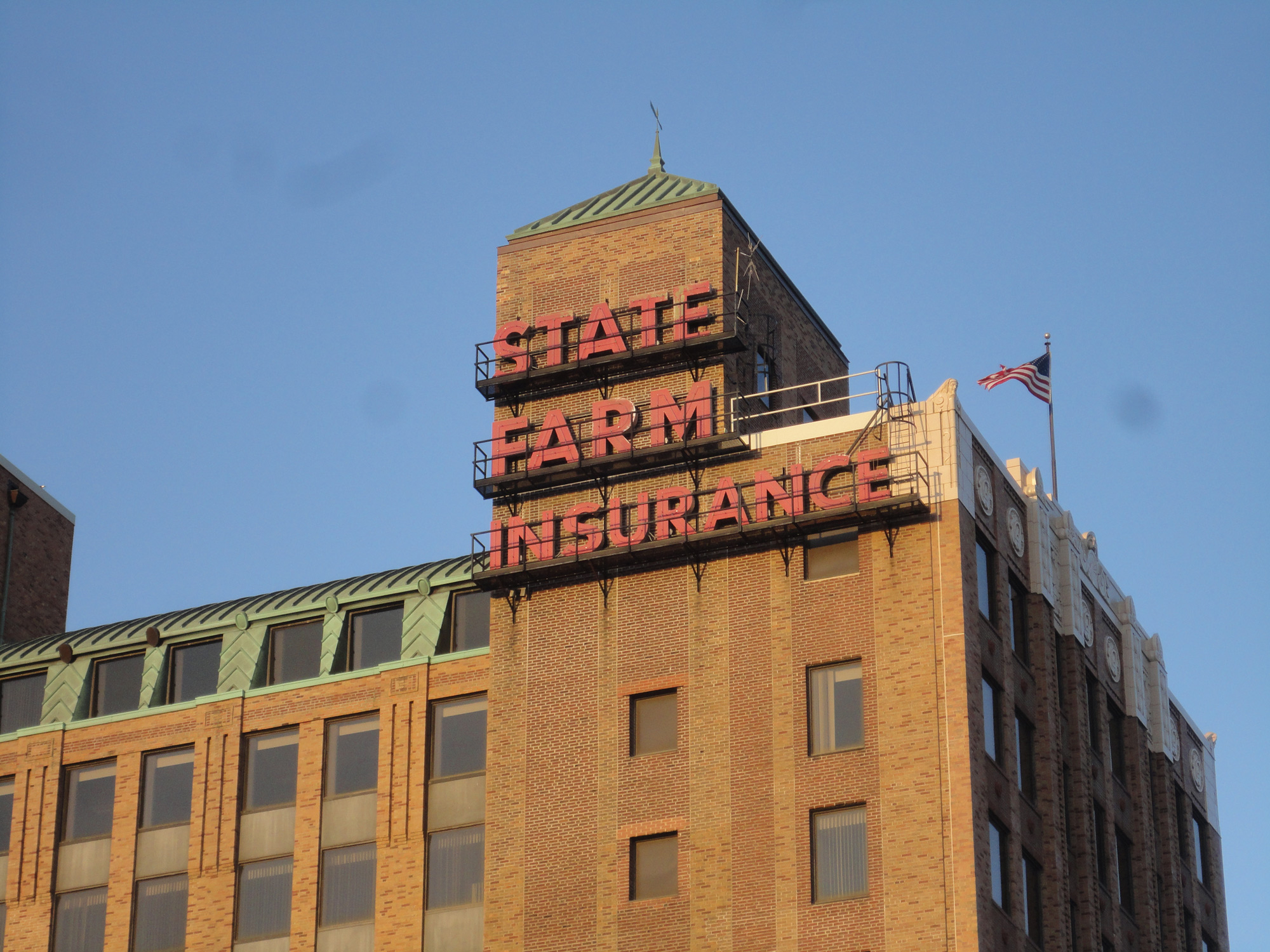 戴着亮红色帽子的国家农场保险公司在棕色砖石建筑的顶部。