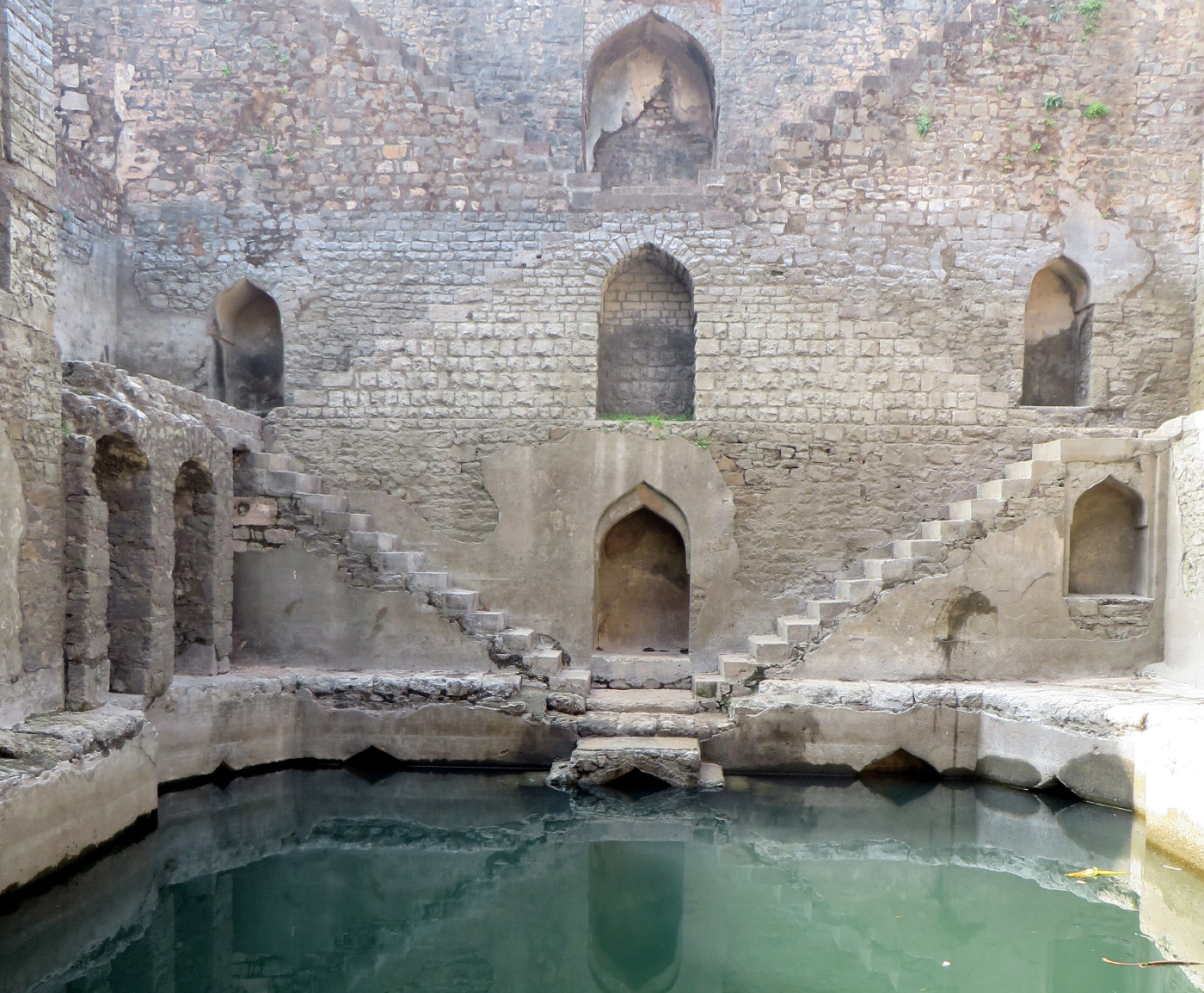 台阶井的照片，楼梯下降到一个水池的水，为印度的地下台阶井展示