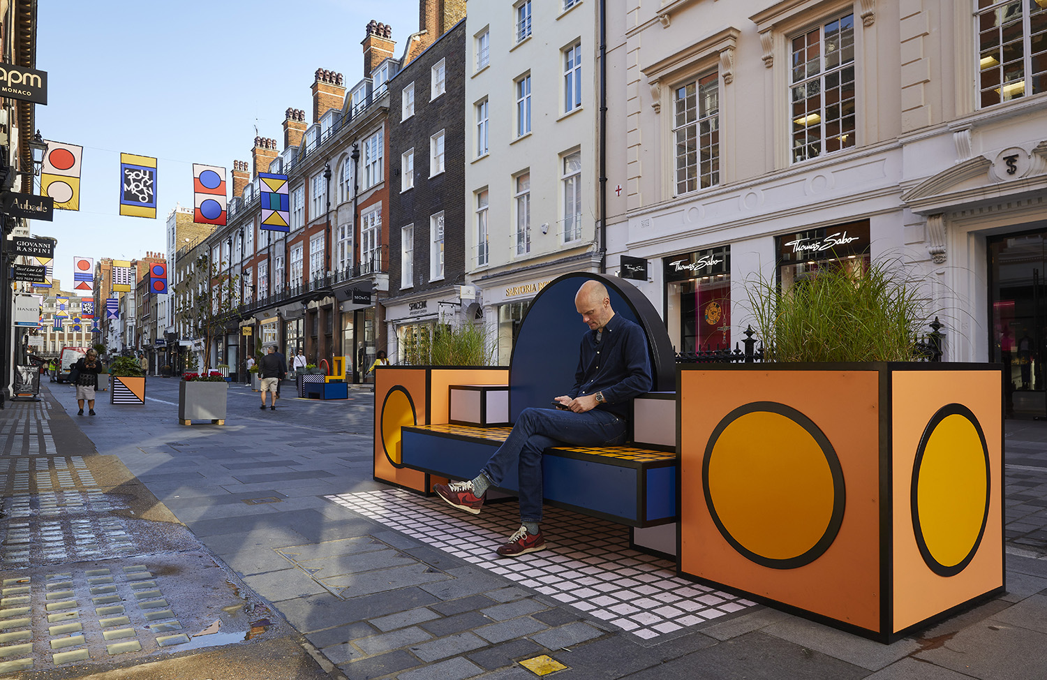一个人的照片坐橙色长凳在伦敦设计节日