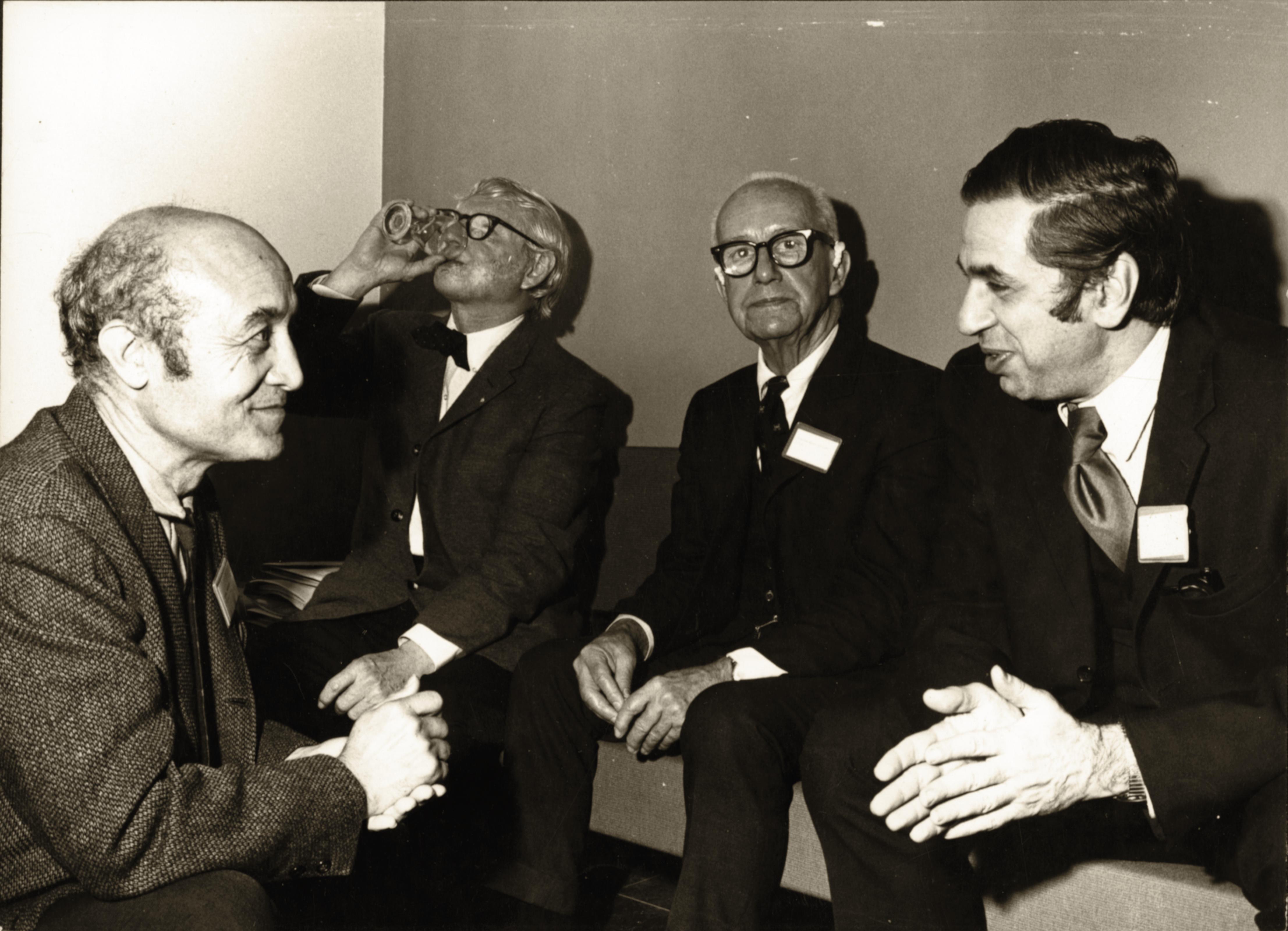 一张黑白照片，照片上有四名男子在喝酒聊天，其中包括野口勇