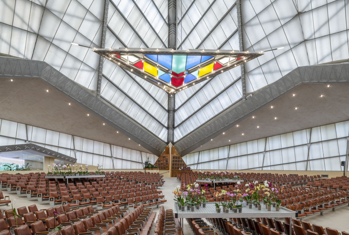 一个彩色玻璃三角形悬挂在座位和鲜花的金字塔形屋顶下。