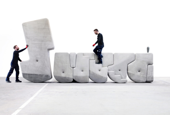 Two people moving large concrete blocks of diifferent shapes