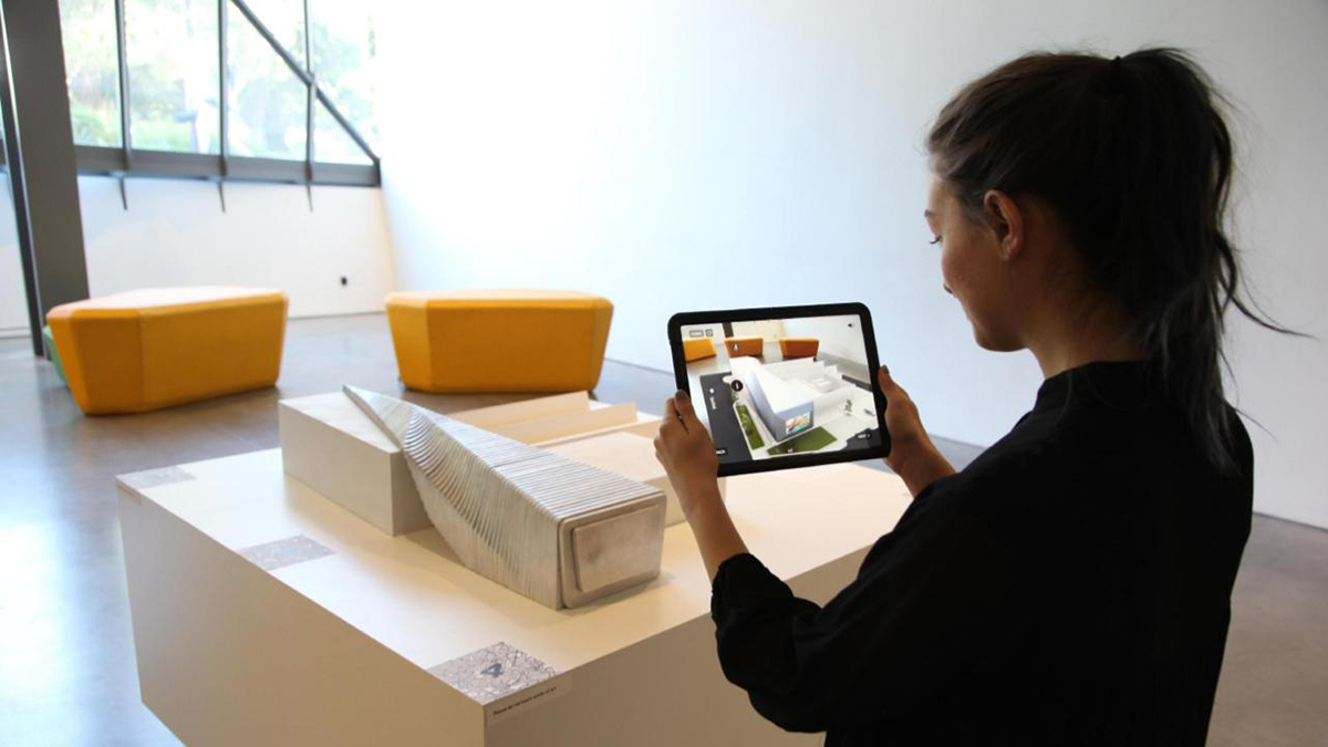 使用iPad在BAMPFA模型上观看AR效果的人。