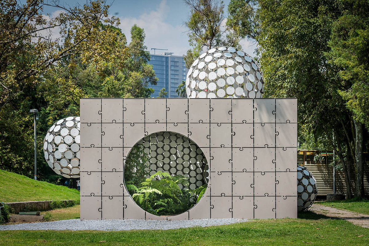 一个混凝土立方体馆，与拼图片状面板，具有由白色圈子制成的球茎形式。