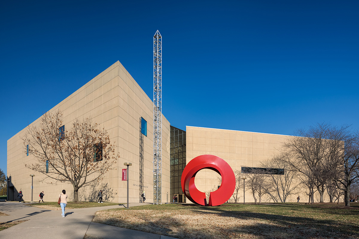 一座石灰岩覆盖的博物馆的外部图像和它前面草坪上的红色圆形雕塑