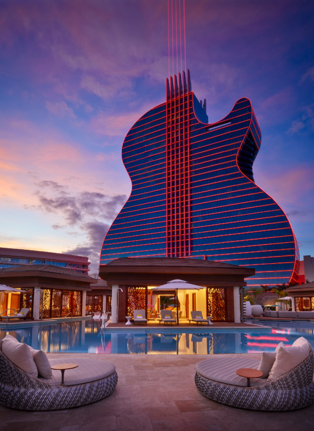 这是一家高大的硬石旅馆的照片，形状像一把吉他，在夜晚闪闪发光
