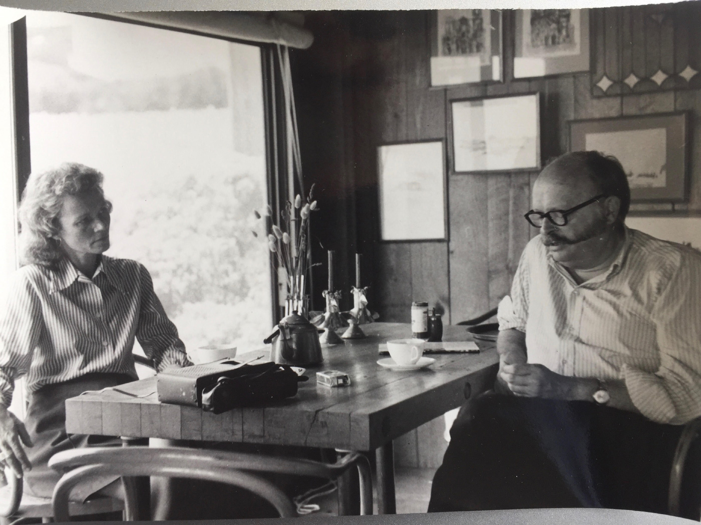 在一张黑白照片中，莎莉·伯恩·伍德布里奇(Sally Byrne Woodbridge)正与桌子旁的一名男子交谈