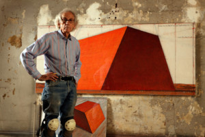 艺术家克里斯托站在一幅橙色金字塔的画前