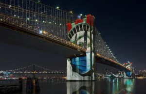 布鲁克林大桥夜间灯火通明，自由女神像投射在桥上