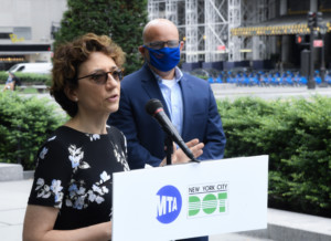 波莉·特罗滕伯格站在领奖台上，手持MTA和DOT徽章