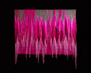 一个粉红色的挂毯与悬挂螺纹