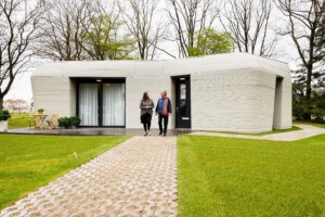 两人走在一块巨石地塑造了3D印刷的房子今天的日常消化