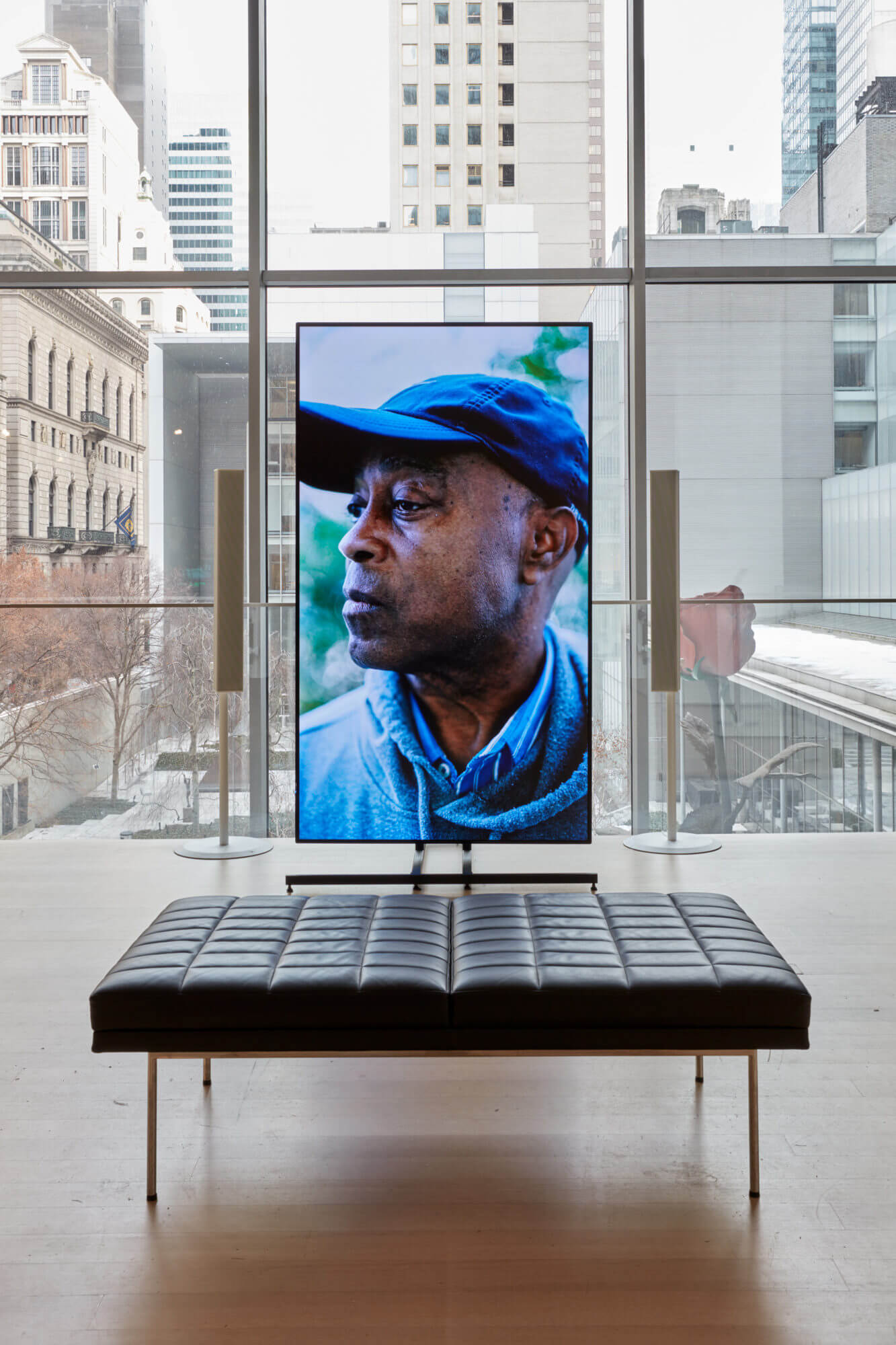 一幅以城市景观为背景，在博物馆画廊中设置垂直方向的视频屏幕的照片