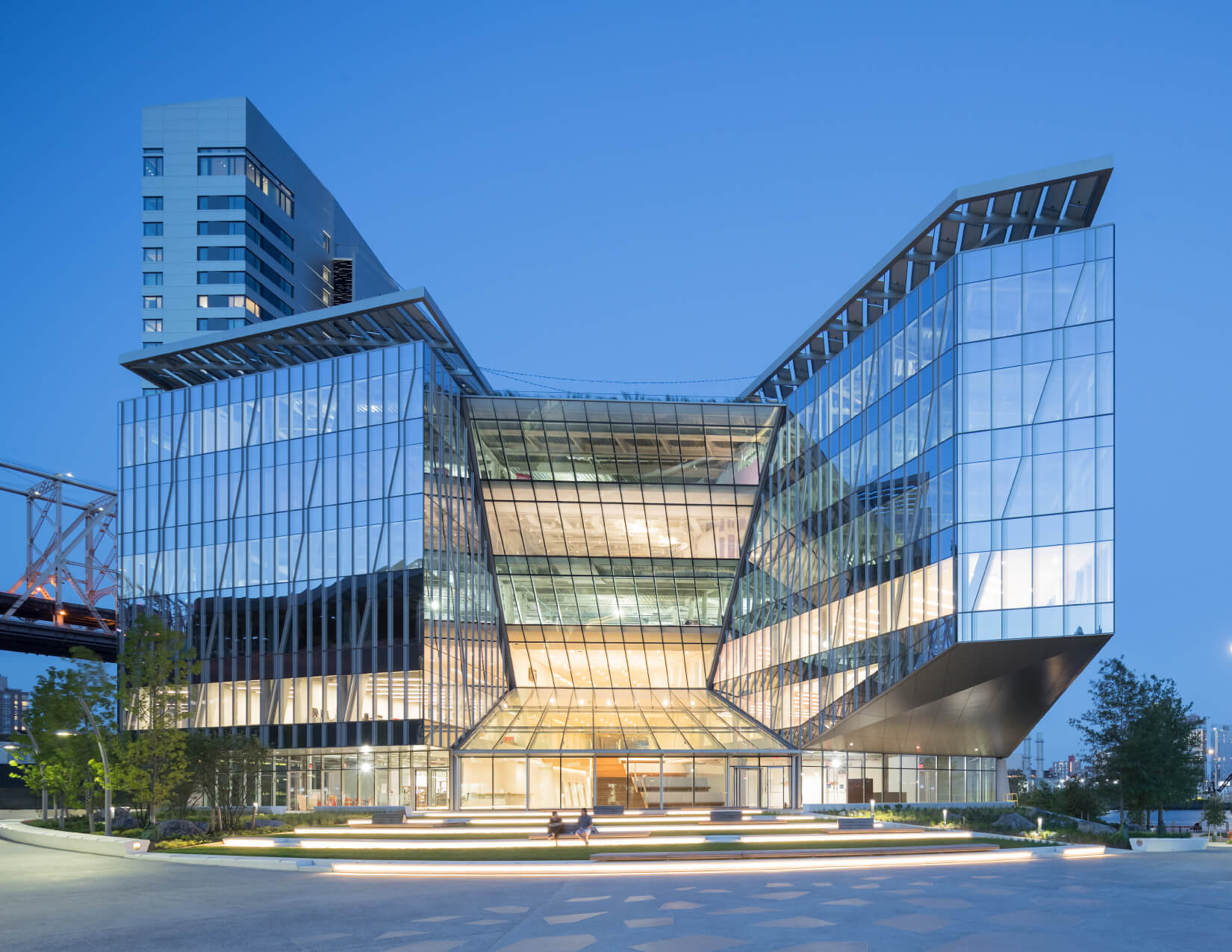 photograph depicting the exterior of a contemporary glass office building at dusk