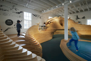 孩子们在新的海湾地区发现博物馆空间内的木制戏剧结构嬉戏
