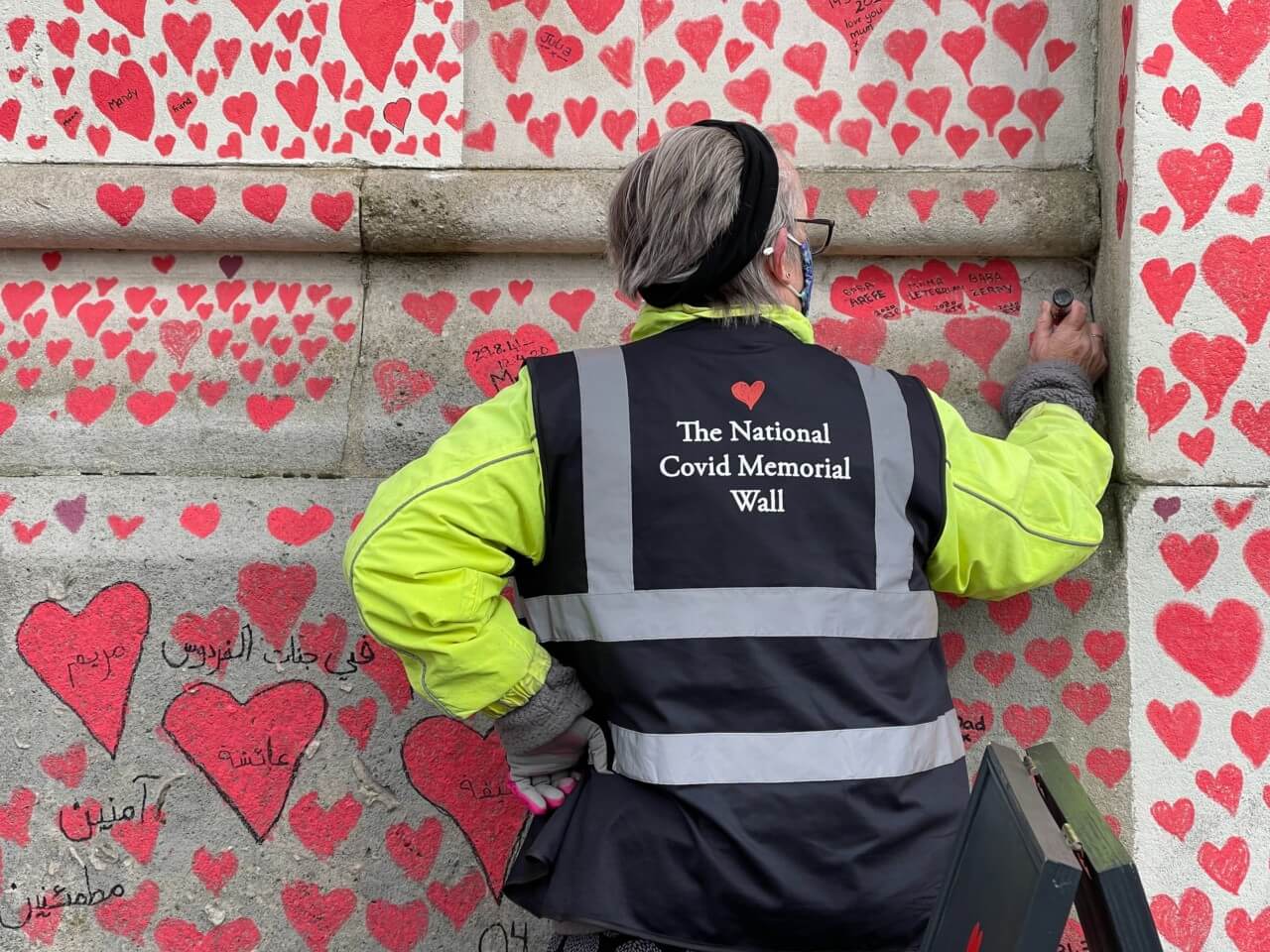 一名工人在新冠肺炎纪念墙上添加了一颗心