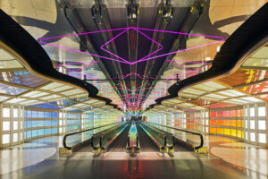 由helmut jahn设计的紫色霓虹灯管和彩色侧壁的机场大厅的内部照片