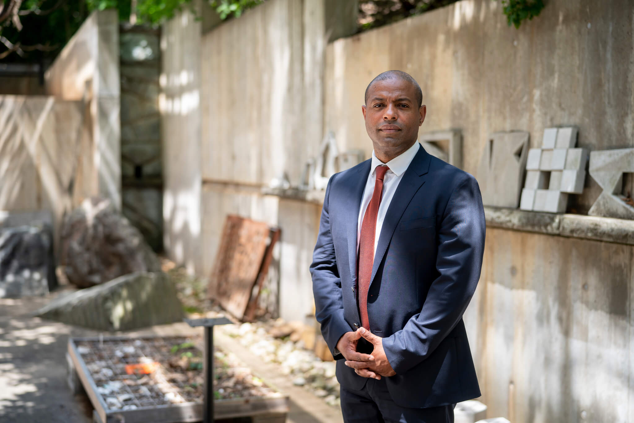 a new dean in a suit and tie against a stone wall
