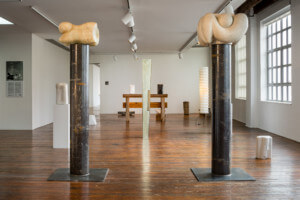 野口博物馆的无用建筑展览的内部照片，展示了夹在两根雕刻柱子之间的雕塑