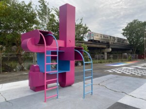 a brightly colored play structure with an elevated train in the background
