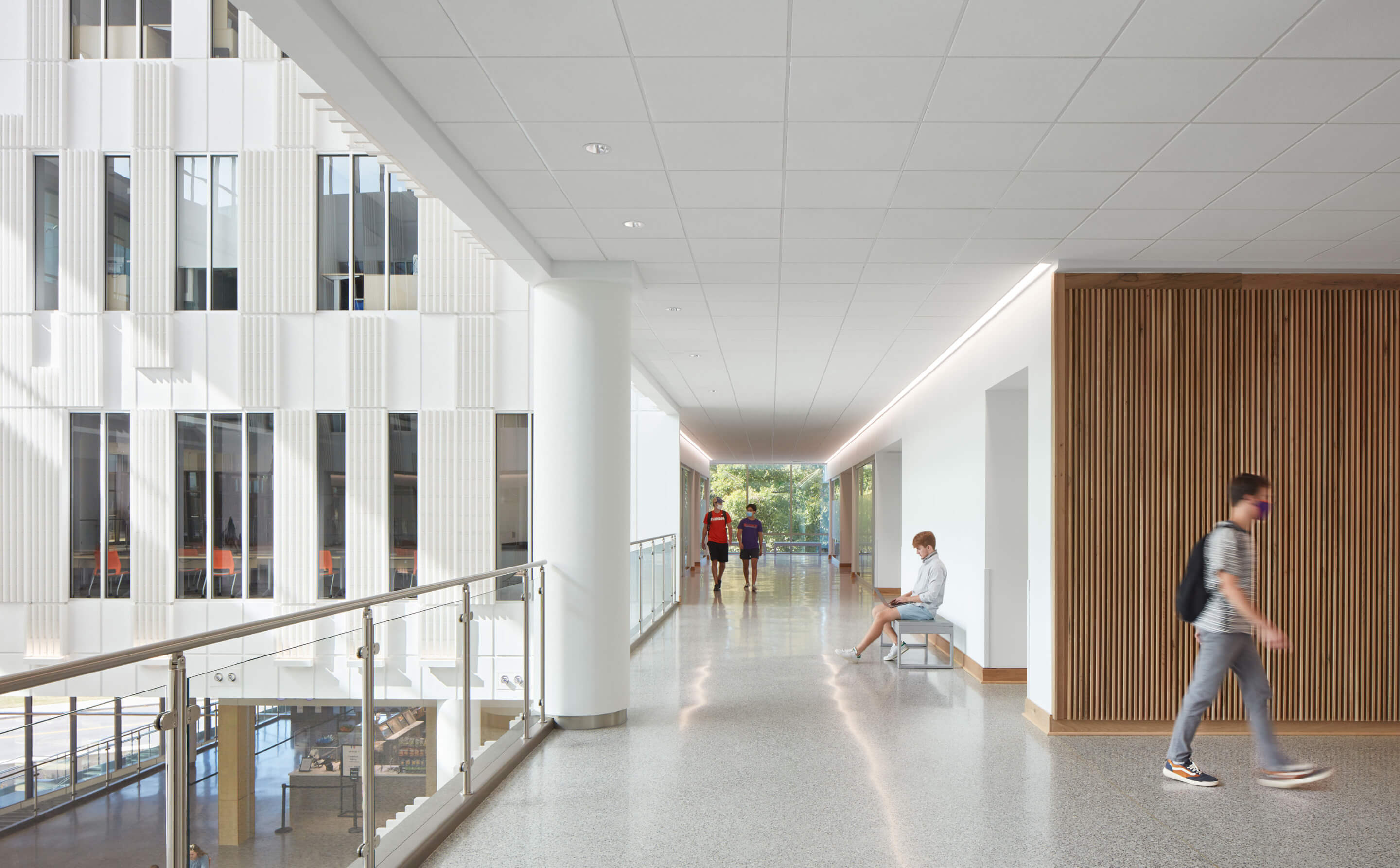 students walk down an open corridor in an airy academic building