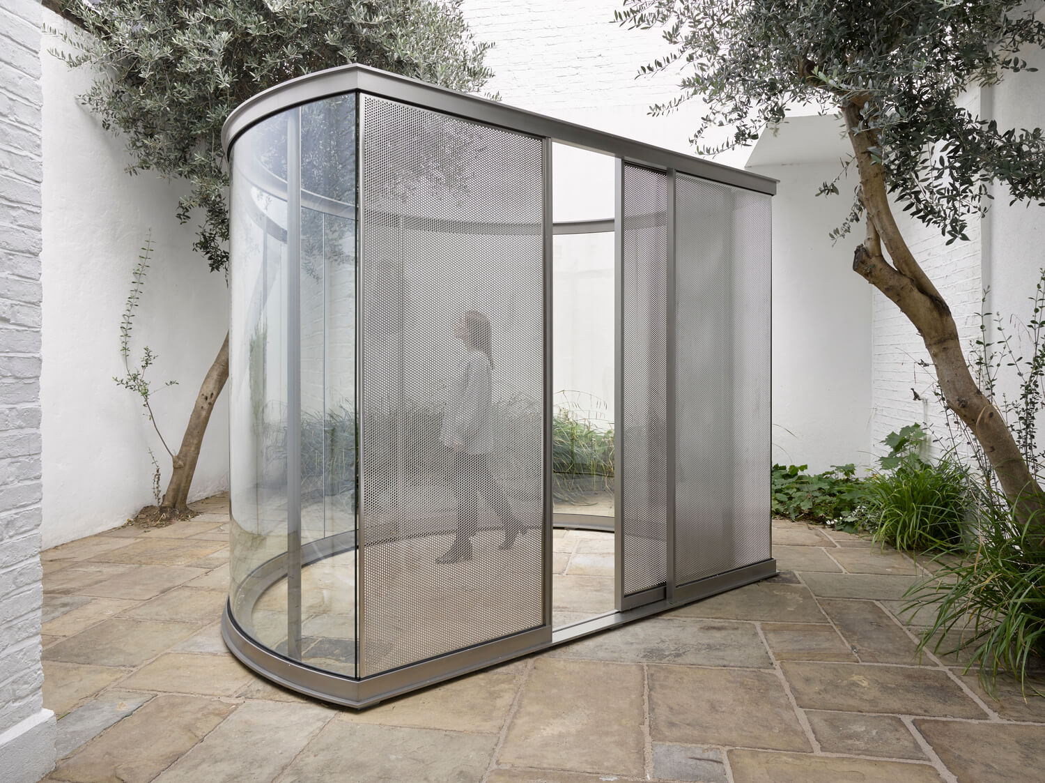 a steel and glass semicircular pavilion on brick